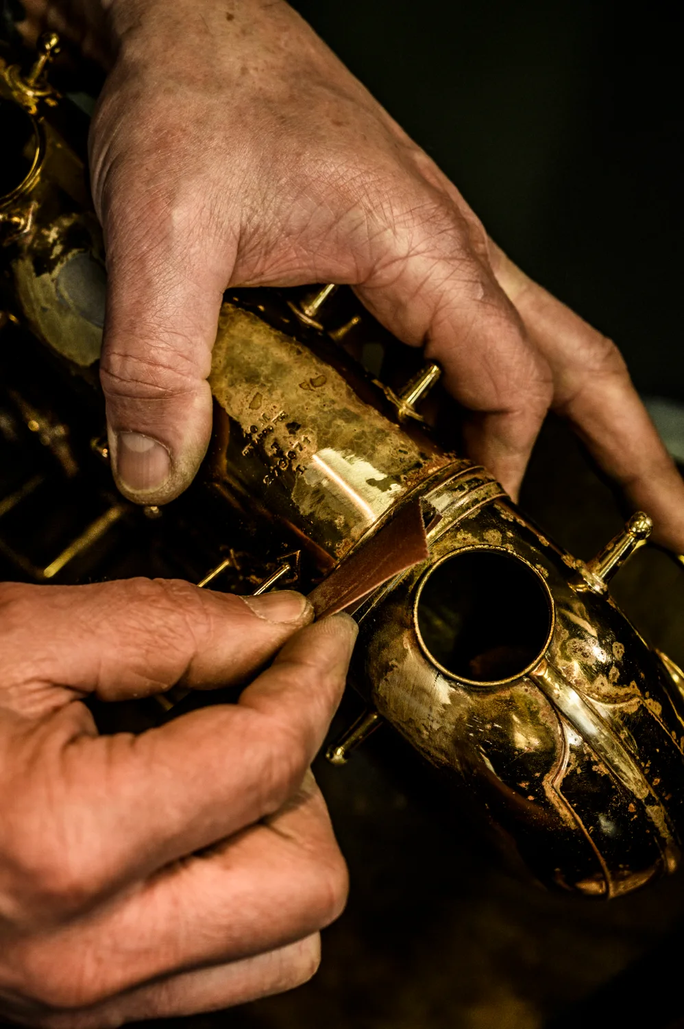Hands sanding a worn saxophone body, close-up — Max Frei, saxophone workshop in Icking near Munich, corporate portraits and editorial photography by Janina Laszlo