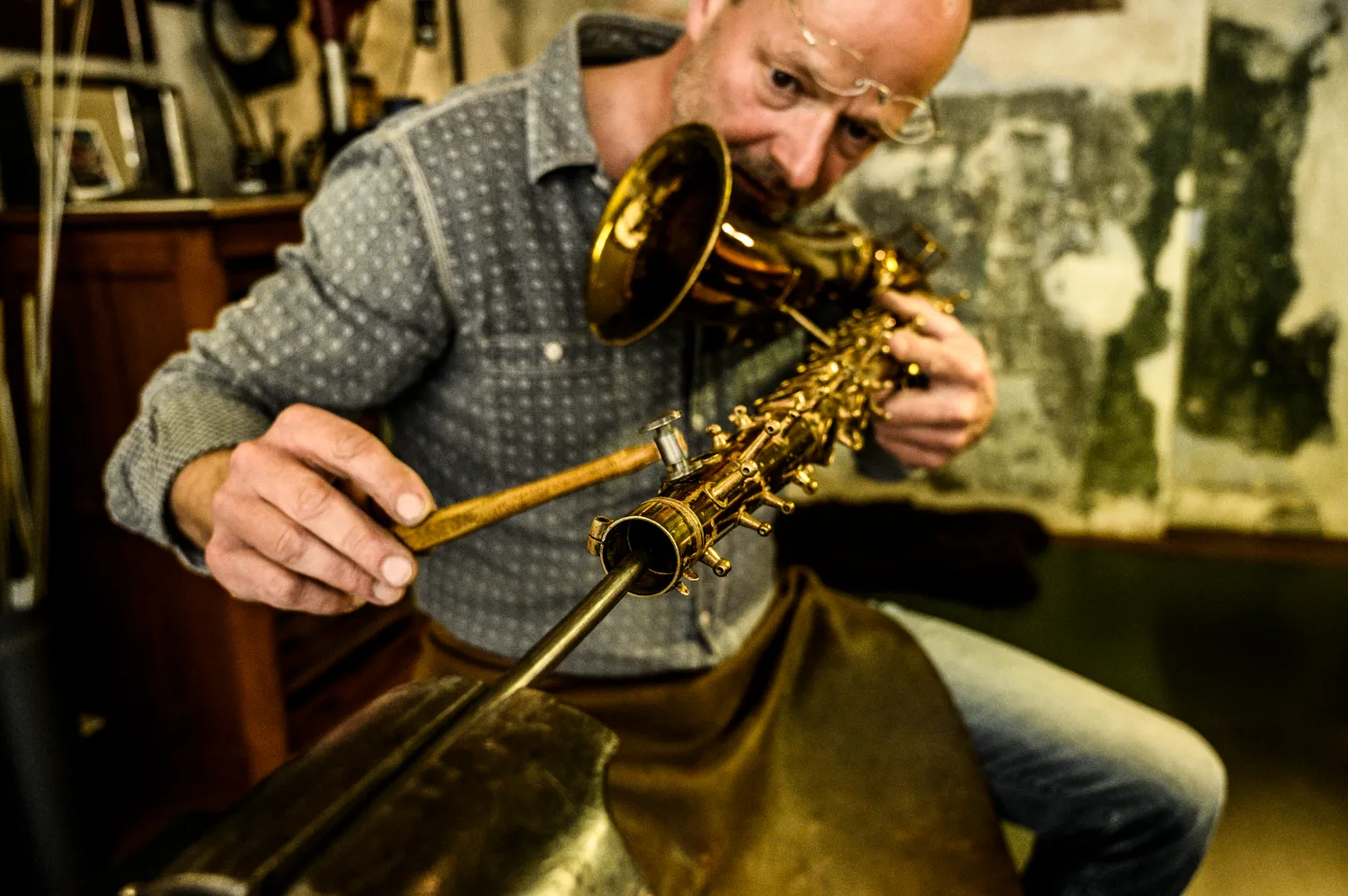 Max Frei adjusting a saxophone tone hole with a mallet on the mandrel — Max Frei, saxophone workshop in Icking near Munich, corporate portraits and editorial photography by Janina Laszlo