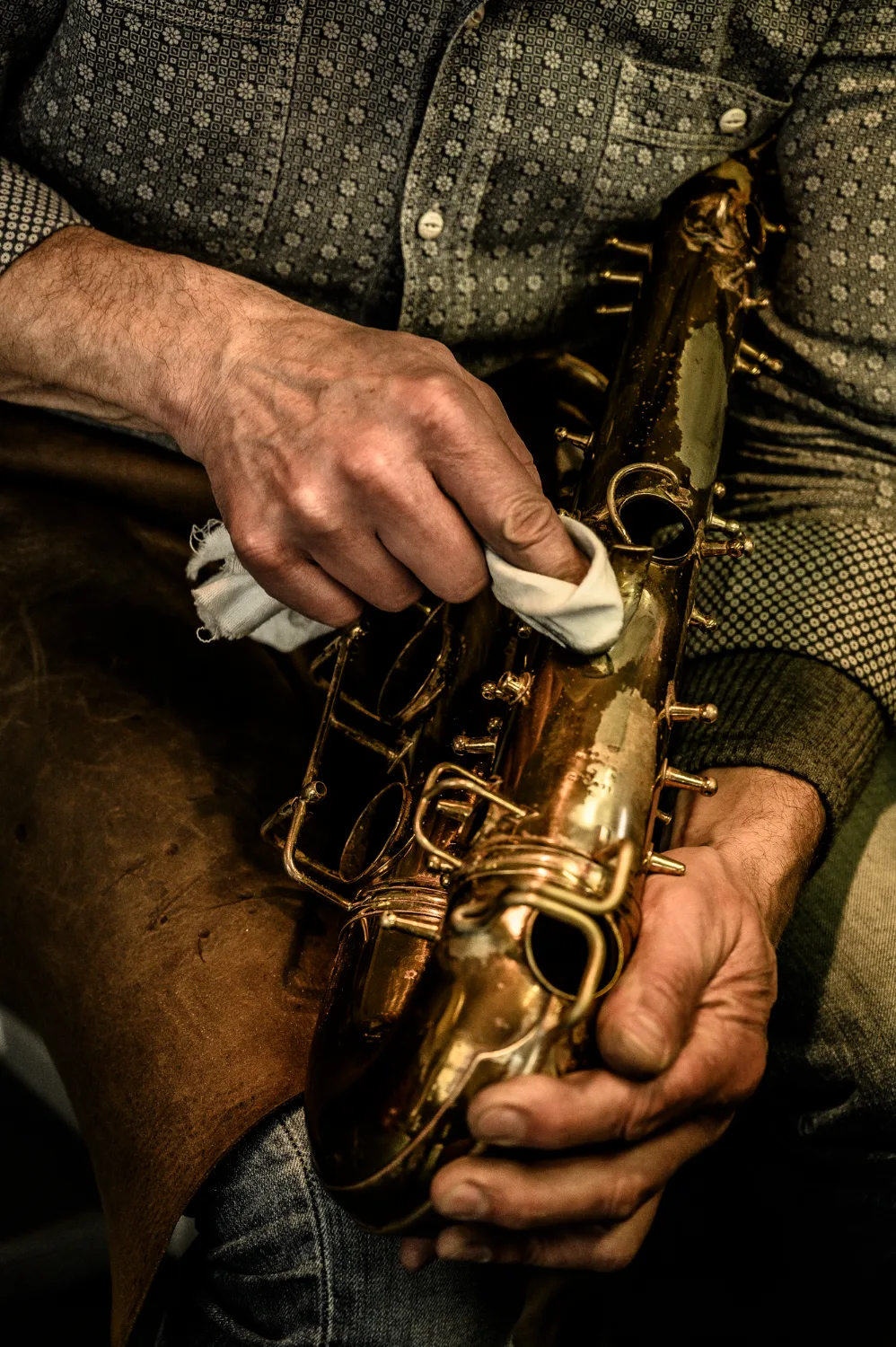 Hands polishing a saxophone with a cloth — Max Frei, saxophone workshop in Icking near Munich, corporate portraits and editorial photography by Janina Laszlo