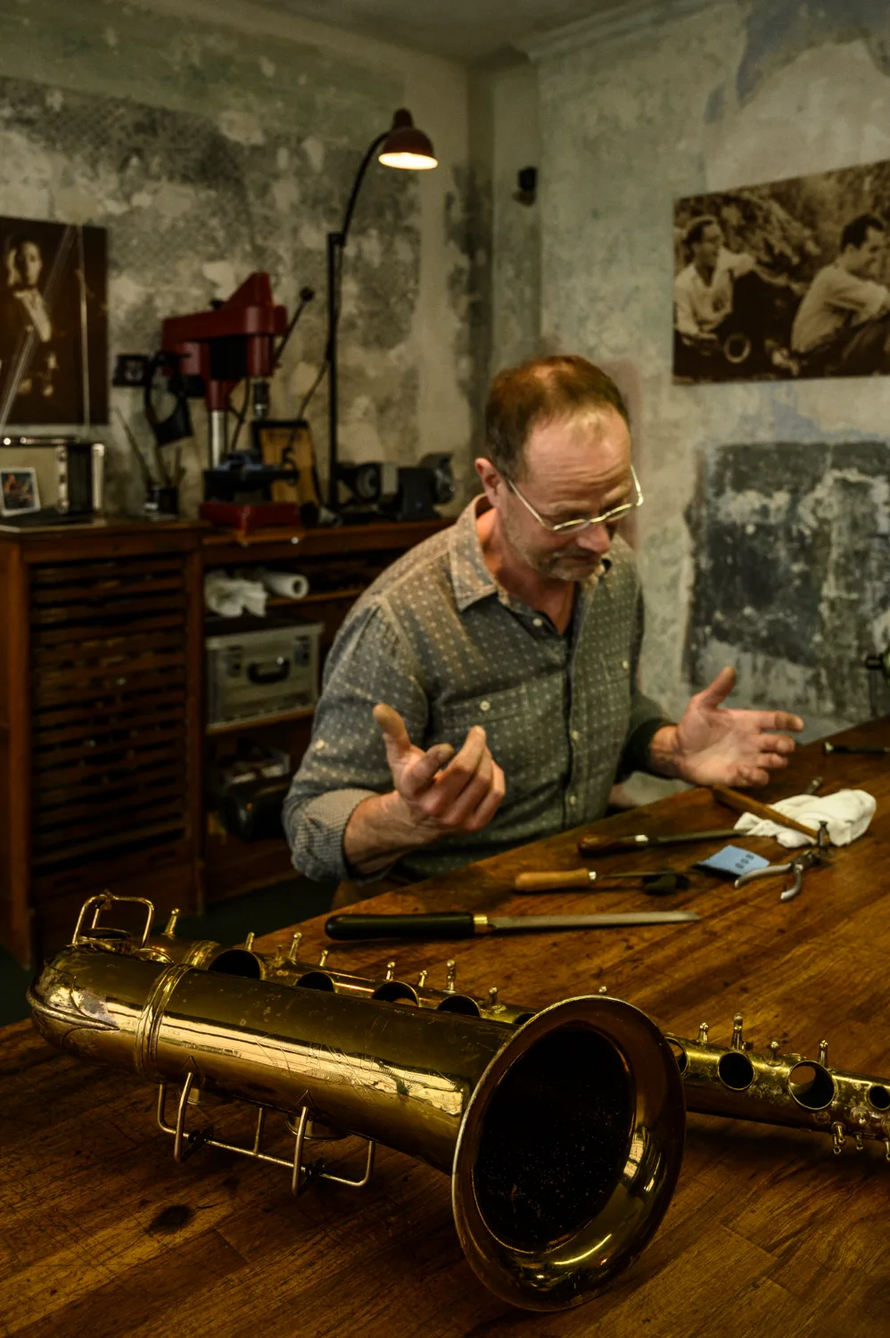 Max Frei explaining over a disassembled saxophone at the workbench — Max Frei, saxophone workshop in Icking near Munich, corporate portraits and editorial photography by Janina Laszlo