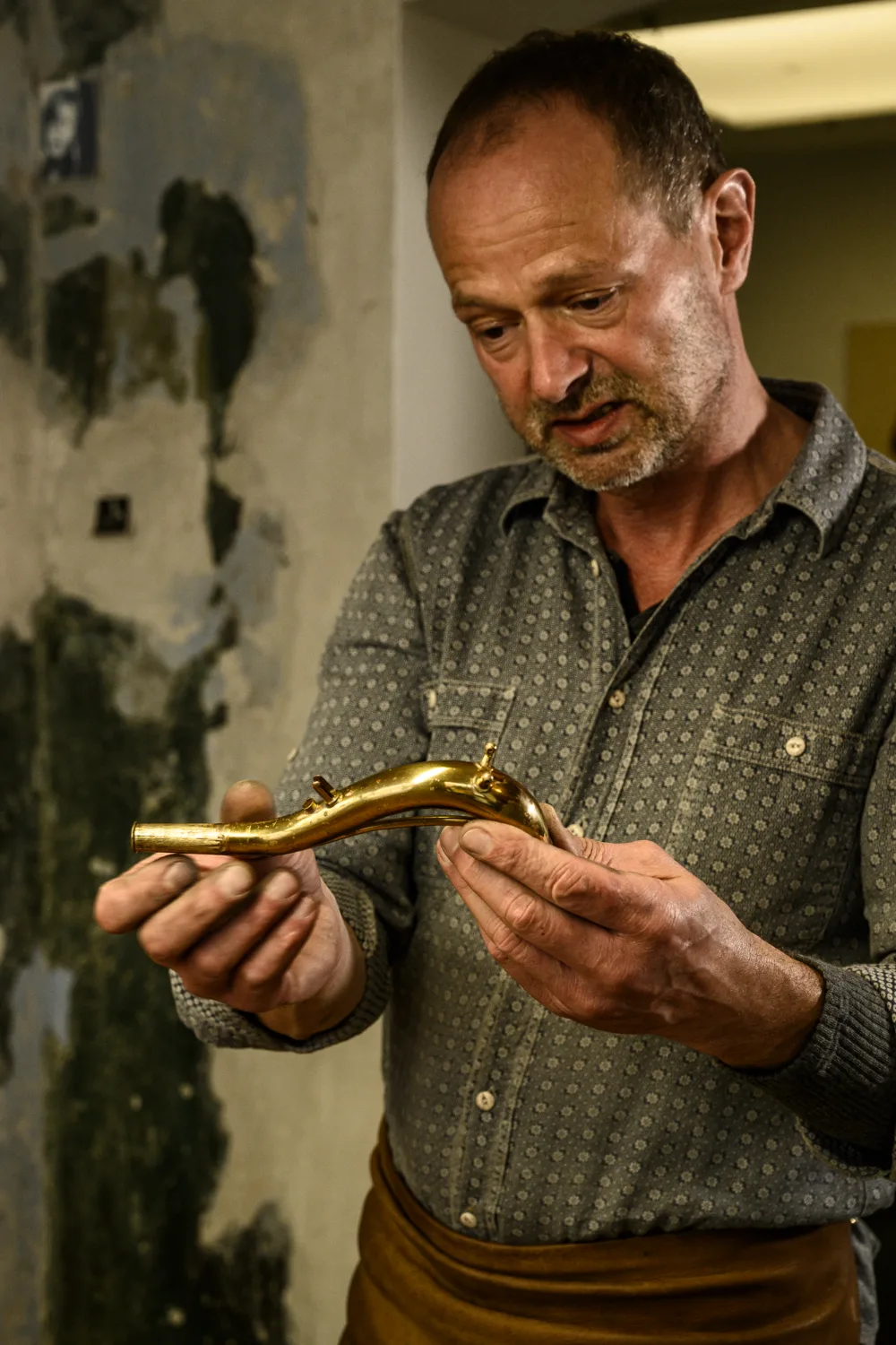Max Frei examining a saxophone neck — Max Frei, saxophone workshop in Icking near Munich, corporate portraits and editorial photography by Janina Laszlo