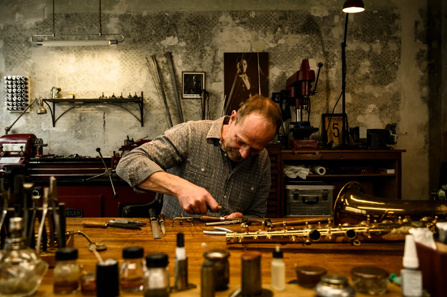 Max Frei bent over the workbench, repairing a saxophone key — Max Frei, saxophone workshop in Icking near Munich, corporate portraits and editorial photography by Janina Laszlo