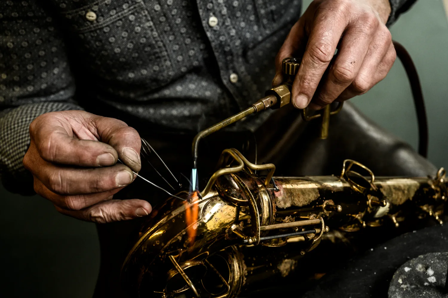 Hands soldering a saxophone with a torch, close-up — Max Frei, saxophone workshop in Icking near Munich, corporate portraits and editorial photography by Janina Laszlo