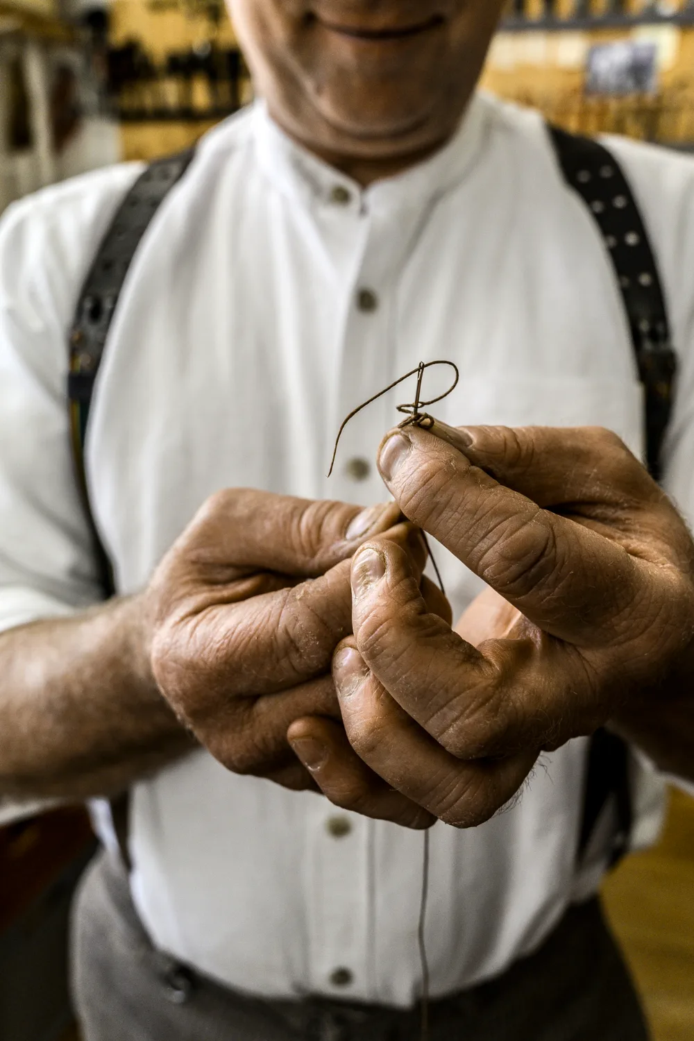 Hands threading a needle with waxed thread, close-up — Michael Ruoff, master saddler, editorial portrait and craftsmanship photography by Janina Laszlo