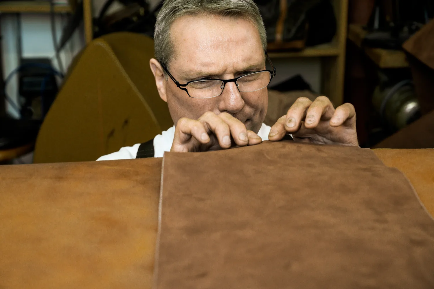 Michael Ruoff inspecting the edge of a leather hide — Michael Ruoff, master saddler, editorial portrait and craftsmanship photography by Janina Laszlo