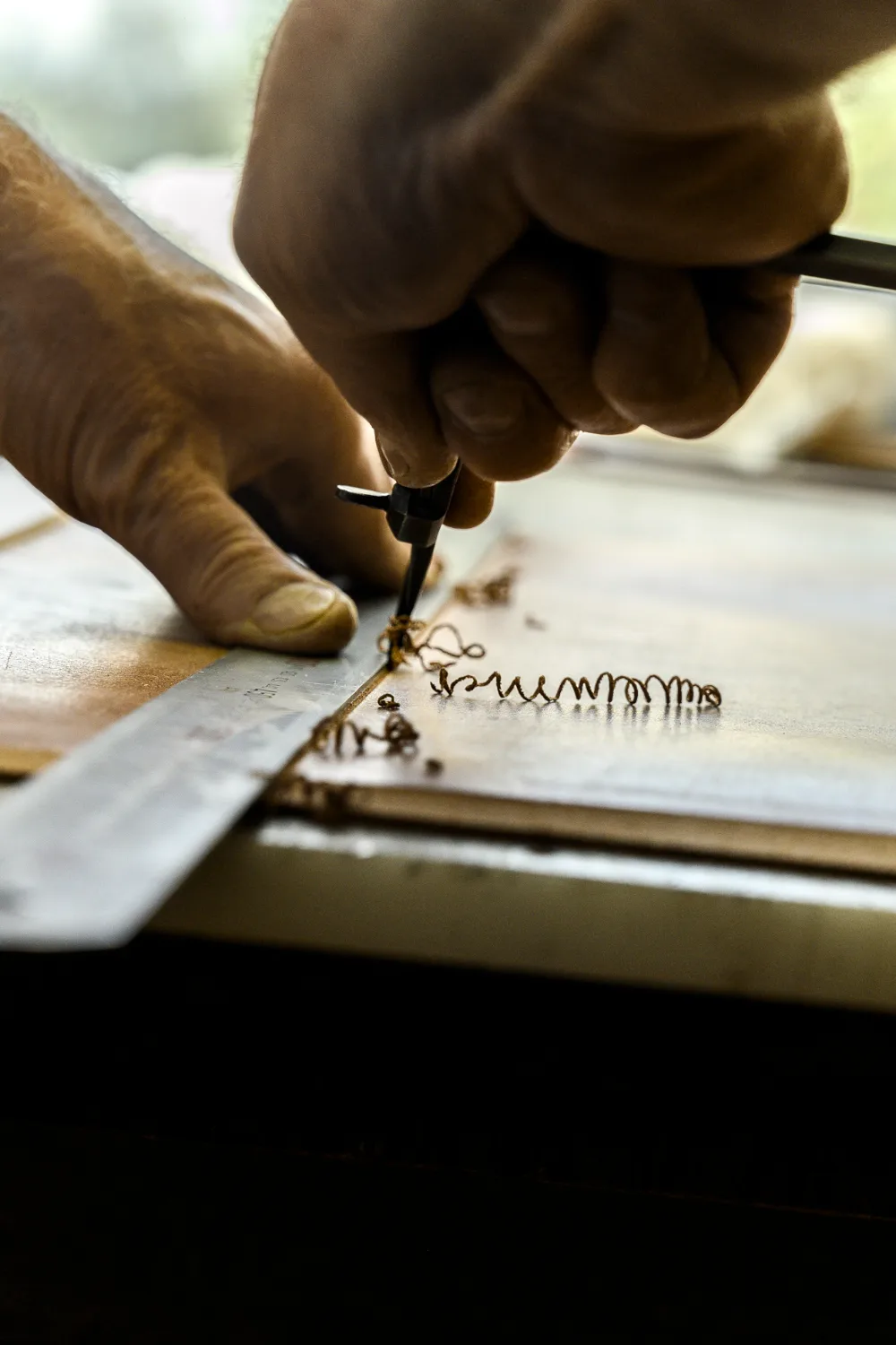 Edge groover cutting a fine leather curl along a steel ruler — Michael Ruoff, master saddler, editorial portrait and craftsmanship photography by Janina Laszlo