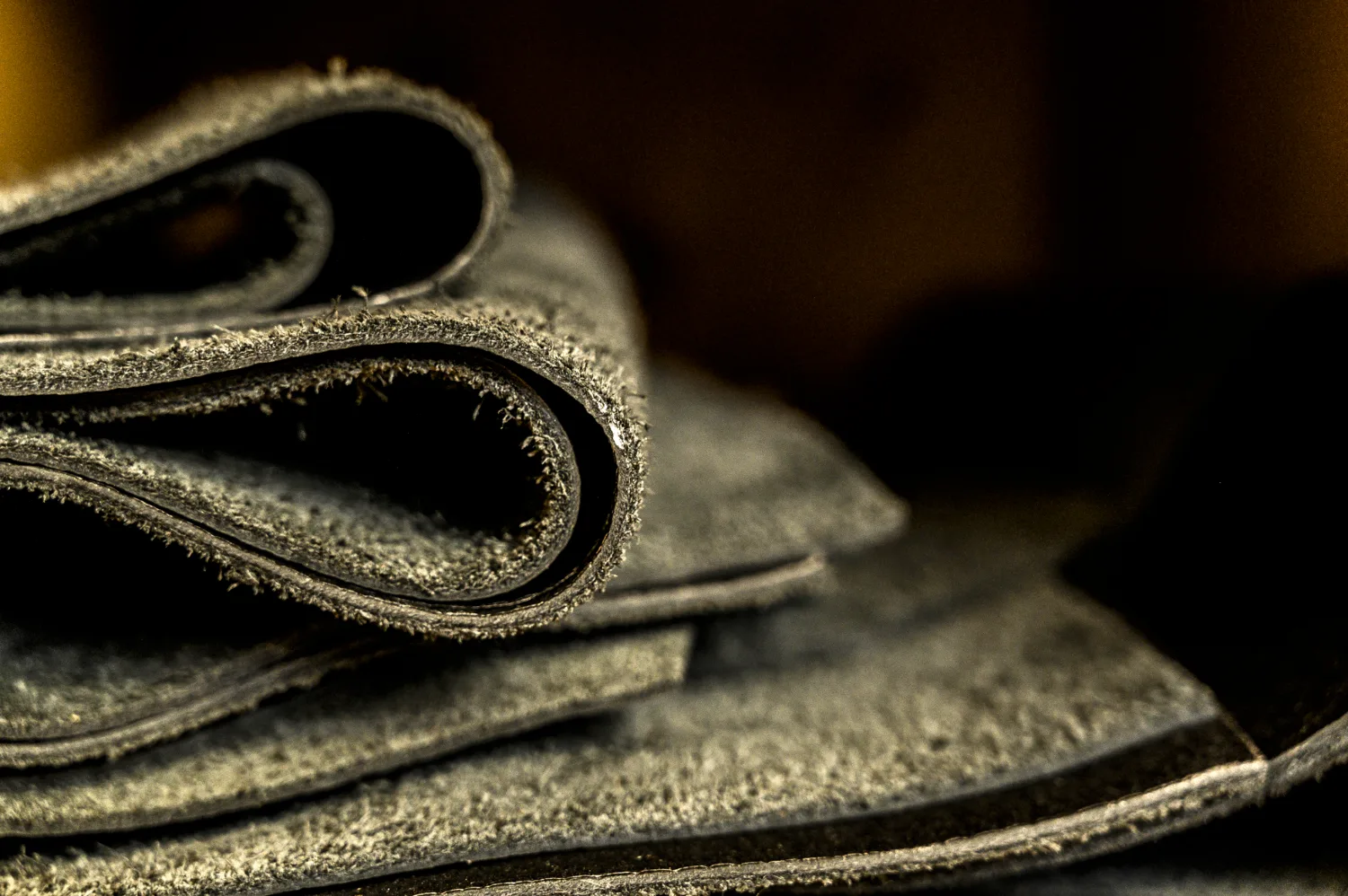 Folded black leather sheets, close-up of the rough edges — Michael Ruoff, master saddler, editorial portrait and craftsmanship photography by Janina Laszlo