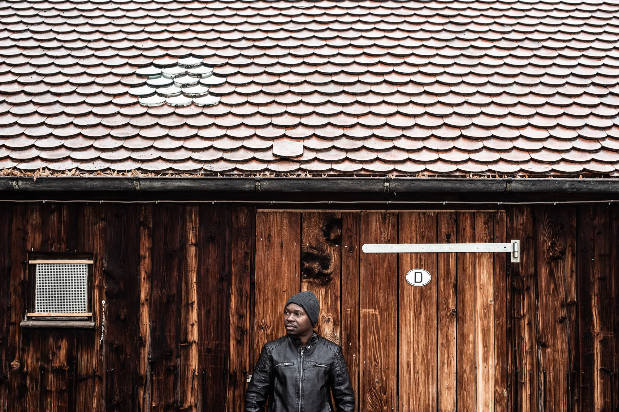 Man standing in front of a wooden barn — MOSES, editorial portrait photography by Janina Laszlo