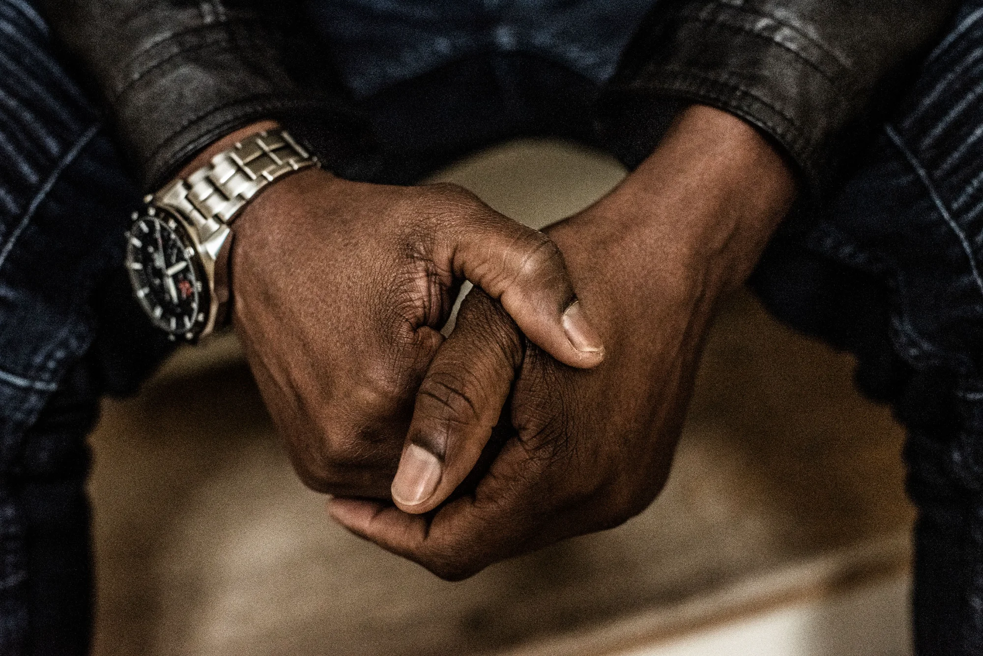 Close-up of folded hands with a wristwatch — MOSES, editorial portrait photography by Janina Laszlo
