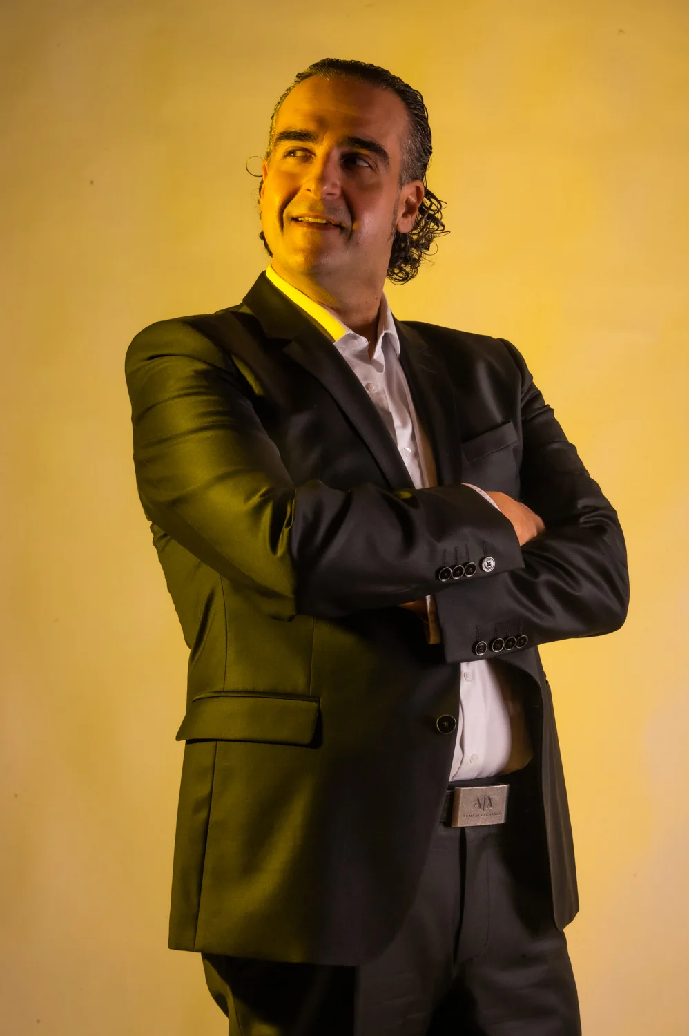 Musician with arms crossed, smiling, warm yellow backdrop — Münchner Symphoniker, musician portrait photography by Janina Laszlo, Munich