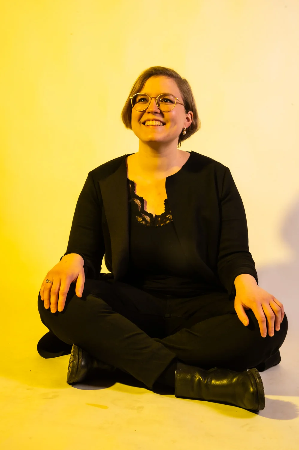 Musician sitting cross-legged on the floor, warm yellow backdrop — Münchner Symphoniker, musician portrait photography by Janina Laszlo, Munich