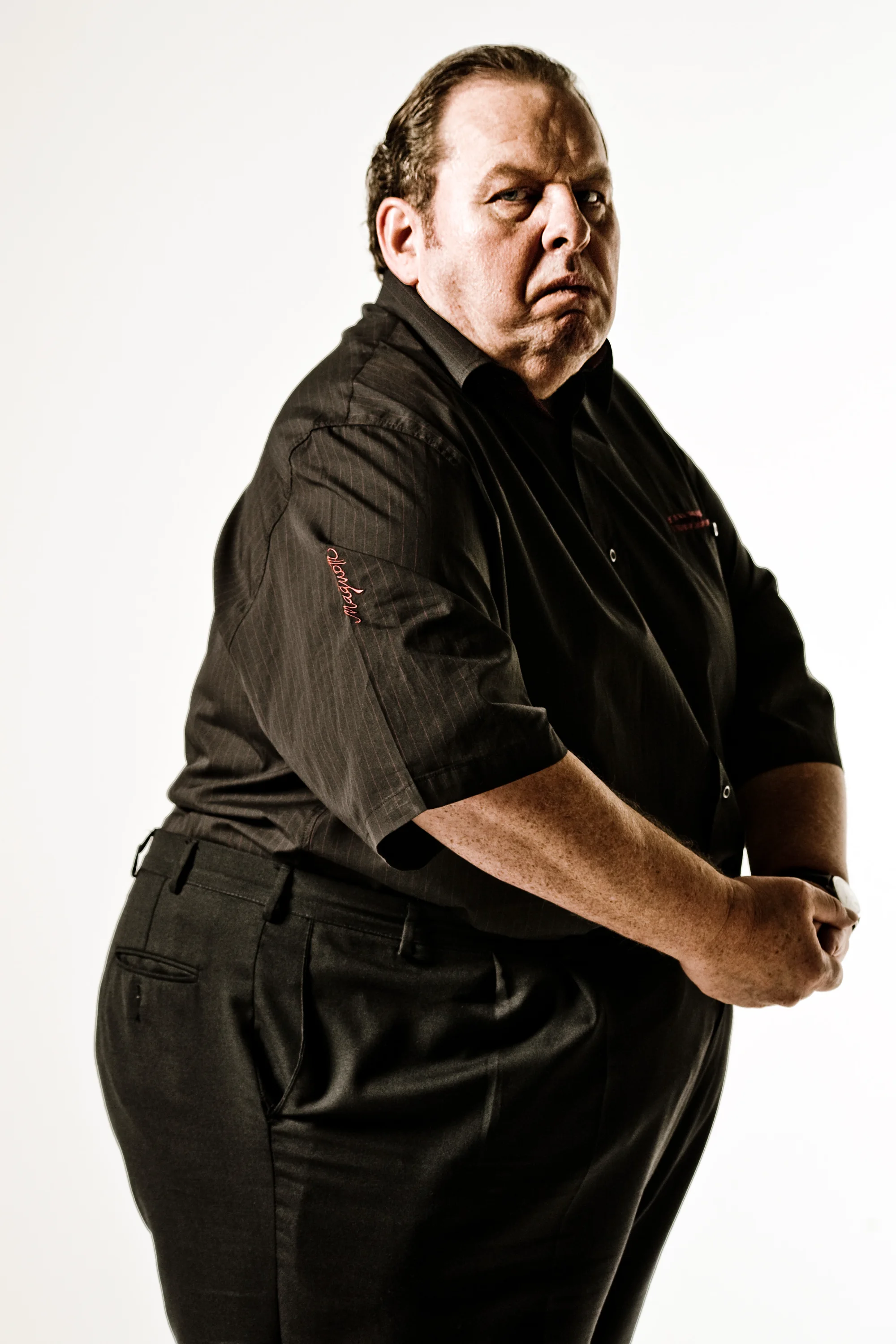 Ottfried Fischer in a black shirt, full-length studio portrait on white — Ottfried Fischer, celebrity portrait photography by Janina Laszlo