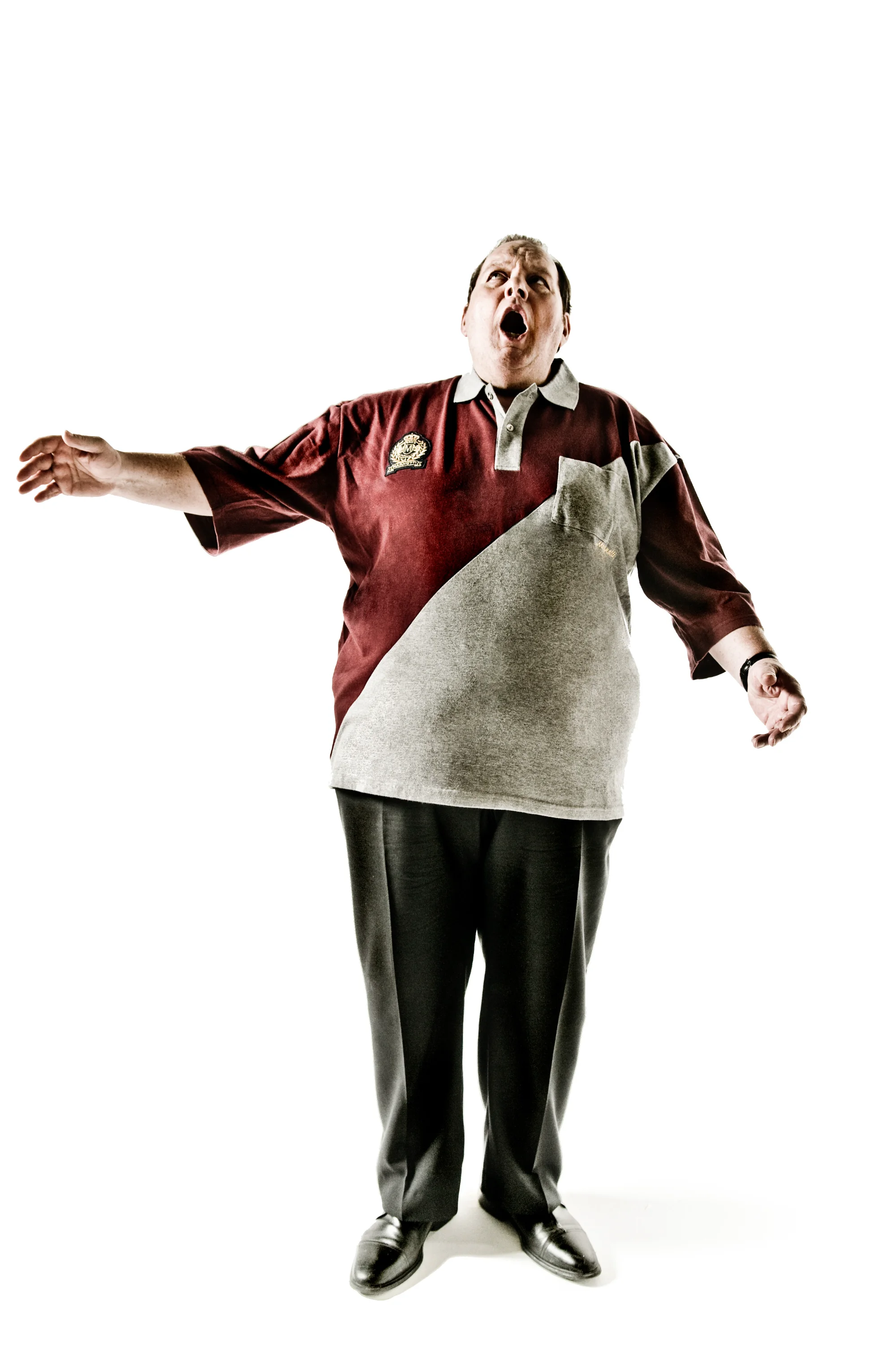 Ottfried Fischer with arms spread wide in a red and white shirt, studio — Ottfried Fischer, celebrity portrait photography by Janina Laszlo