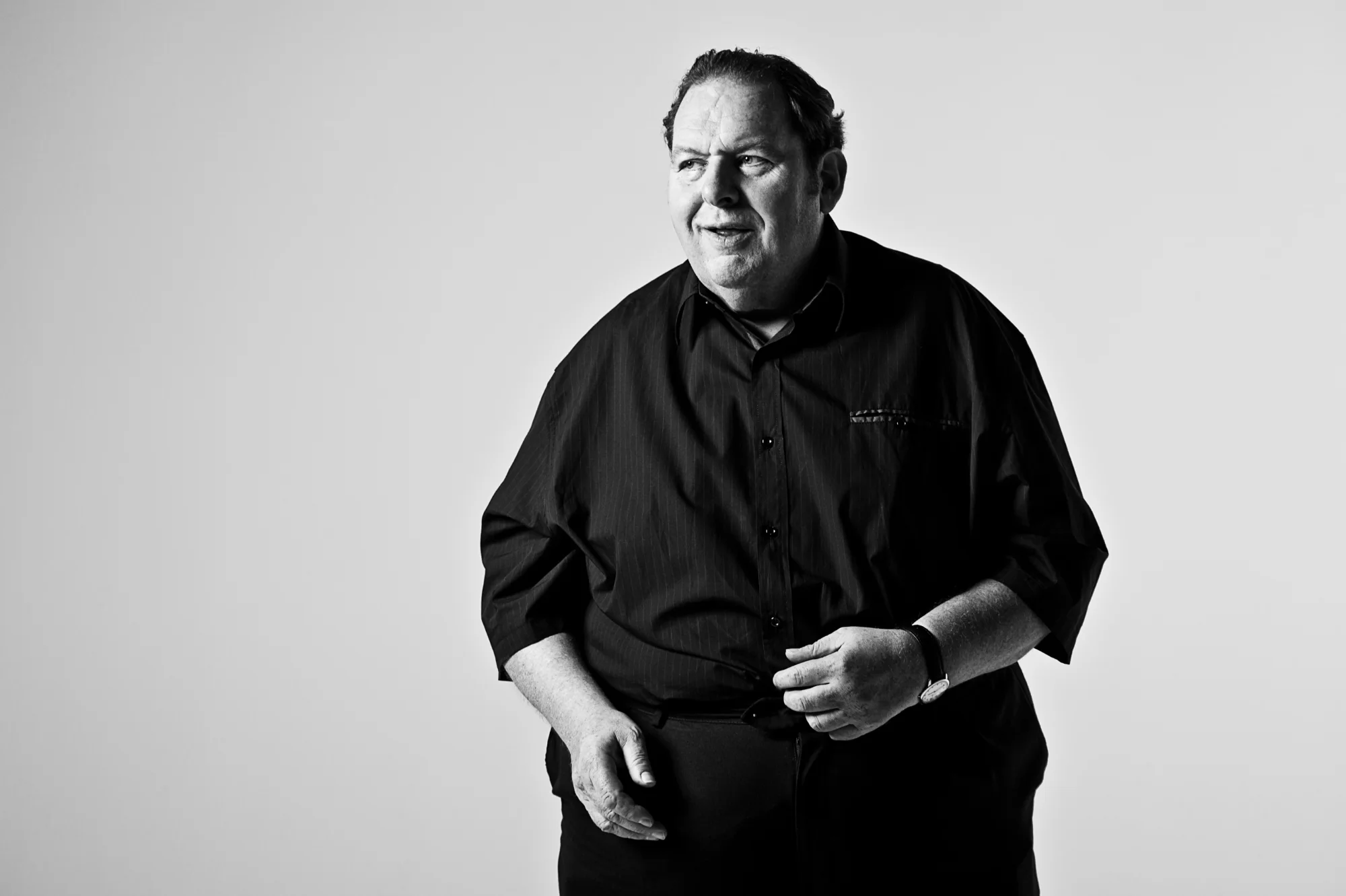 Ottfried Fischer standing in a white studio, black-and-white — Ottfried Fischer, celebrity portrait photography by Janina Laszlo