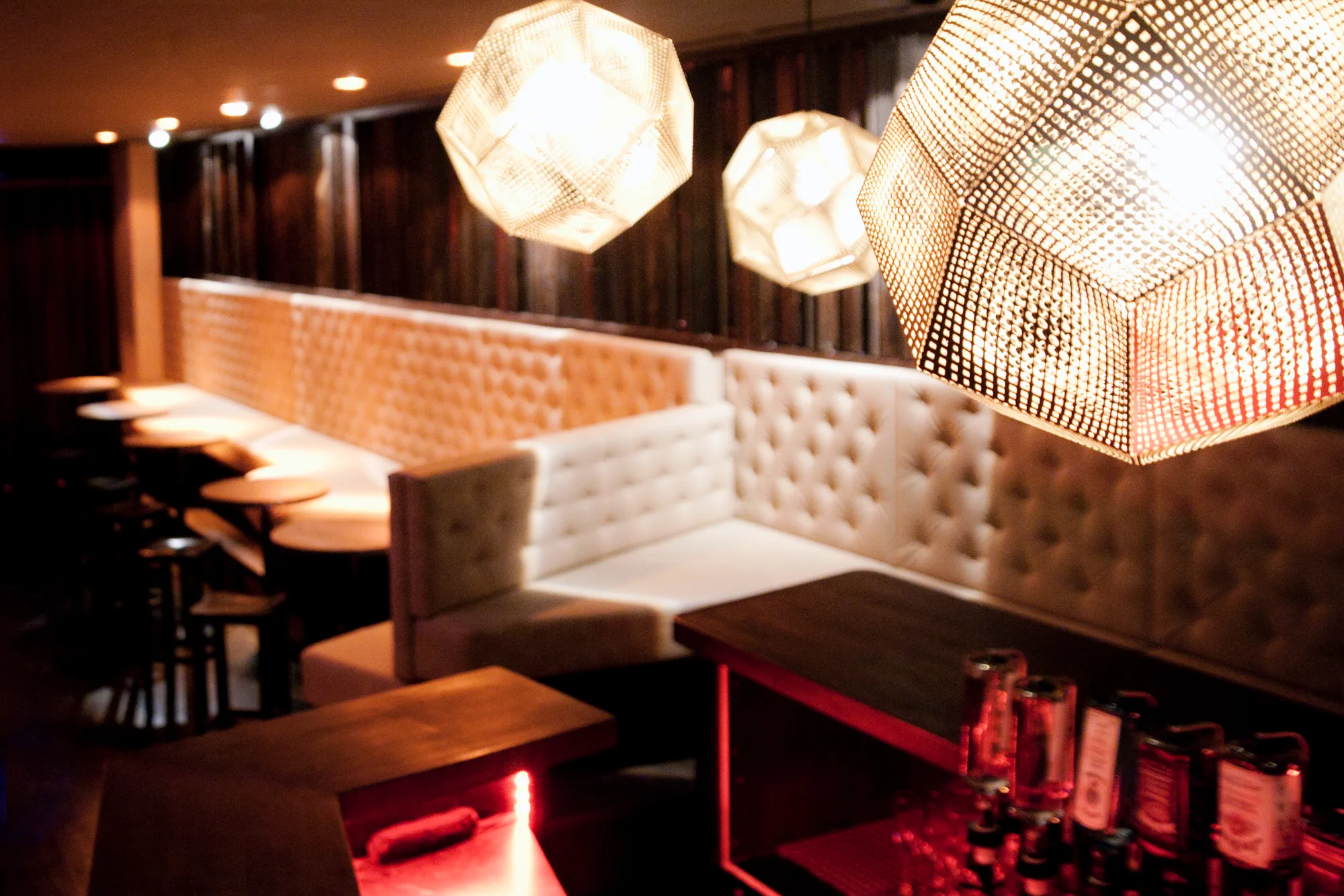 Close-up of perforated geometric pendant lamps above a tufted white leather banquette — Pacha Munich, interior and architectural photography by Janina Laszlo, Munich