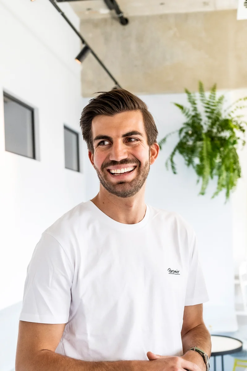 Laughing Personio co-founder in a white Personio T-shirt in the bright office, Munich — Personio, corporate photography by Janina Laszlo