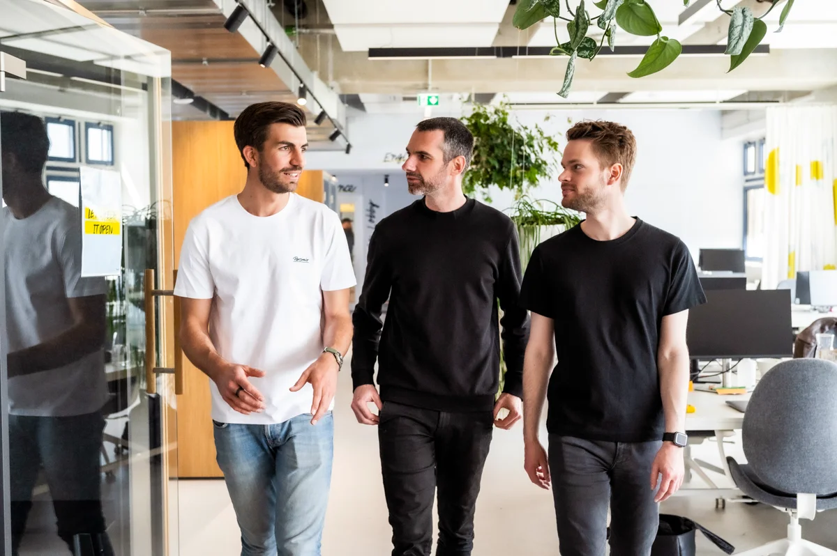 The three Personio founders walking through the open-plan office in conversation, Munich — Personio, corporate photography by Janina Laszlo