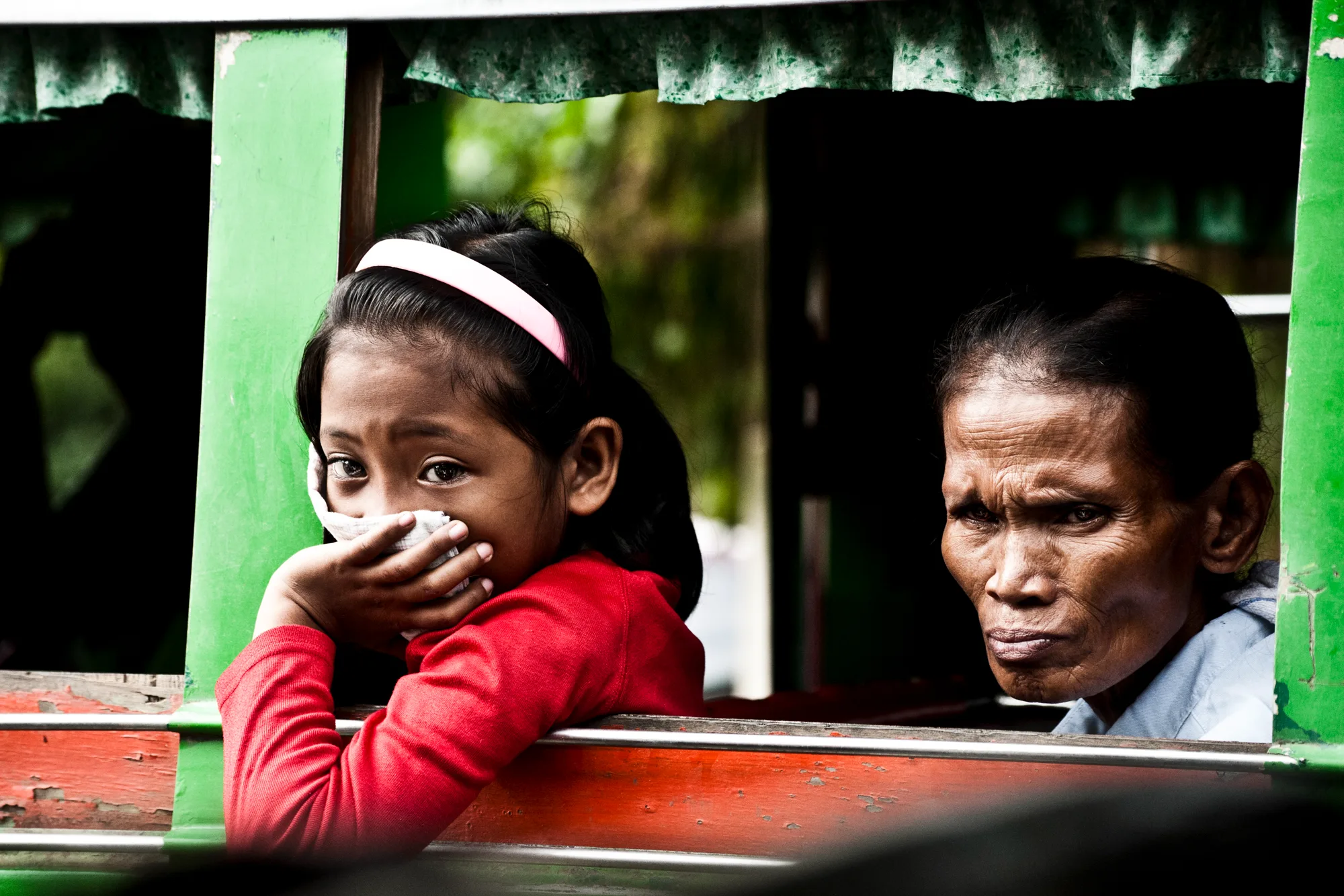 Girl in a red sweater and an older woman looking out of a jeepney window — Palawan, Philippines, documentary and travel photography by Janina Laszlo