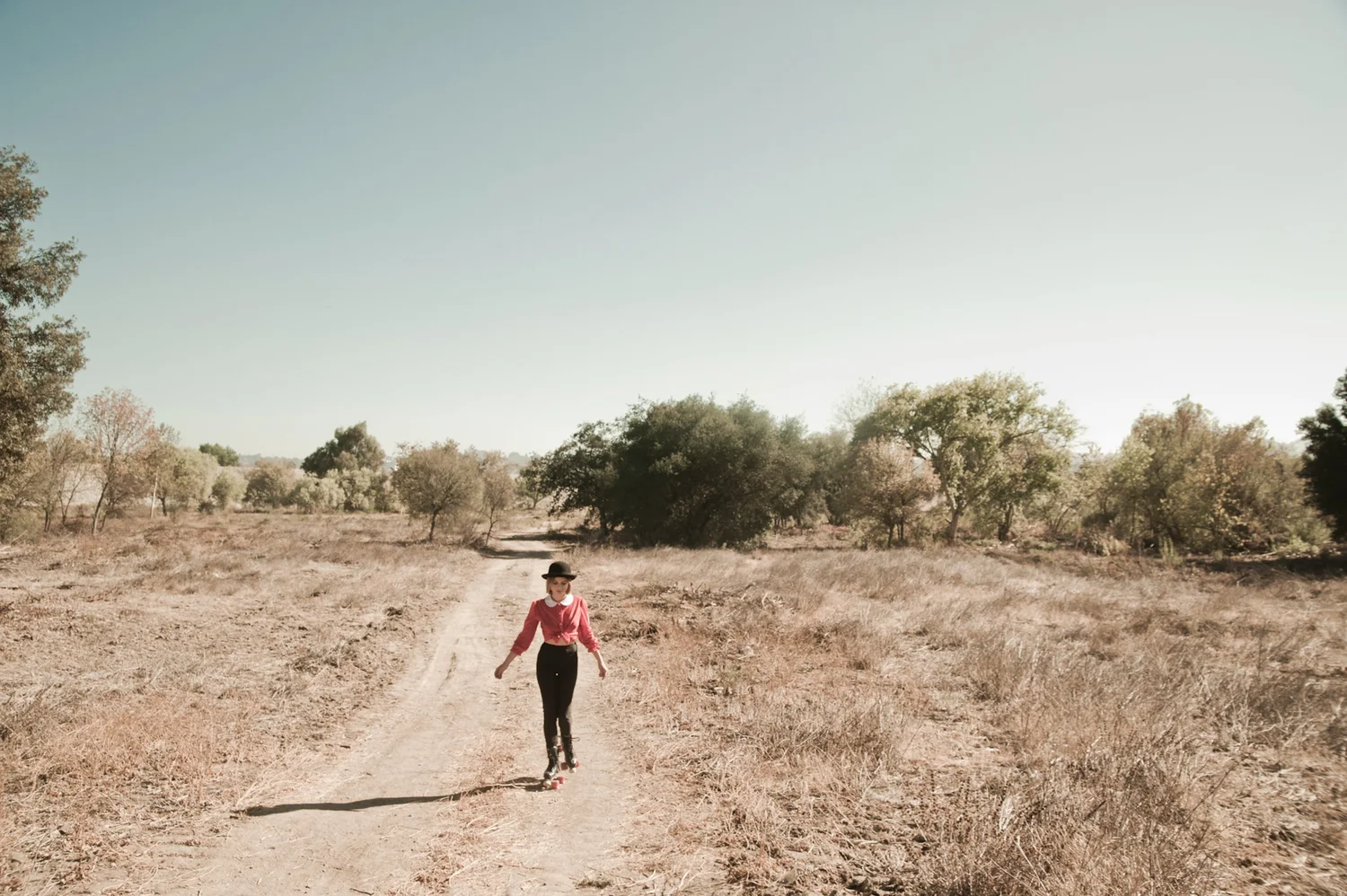 Augie Duke walking alone down a desert dirt road, cinematic wide shot — portrait by Janina Laszlo, portrait photographer in Munich