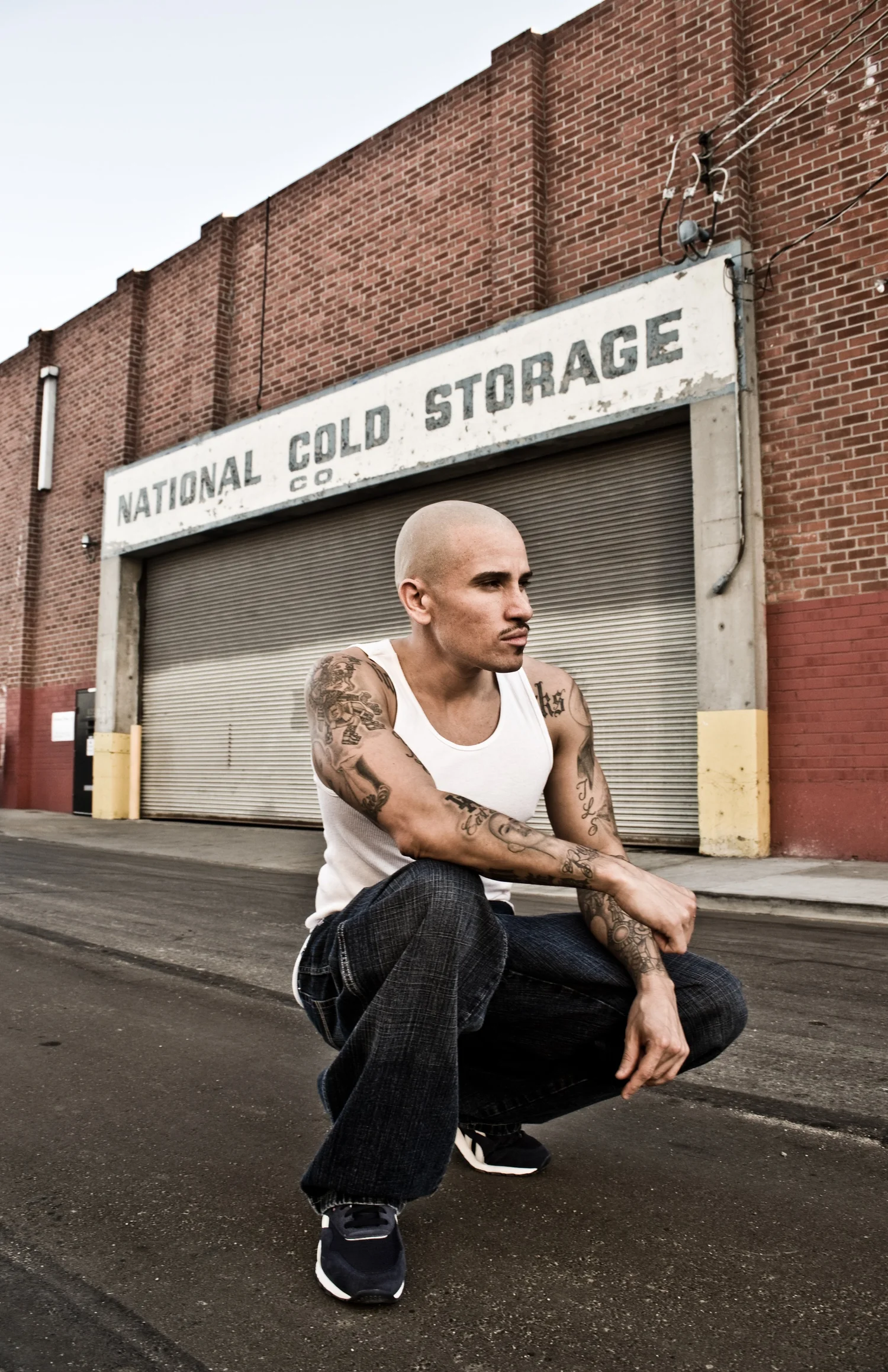 Actor Cesar Garcia crouching in front of a cold storage building in Los Angeles — portrait by Janina Laszlo, portrait photographer in Munich