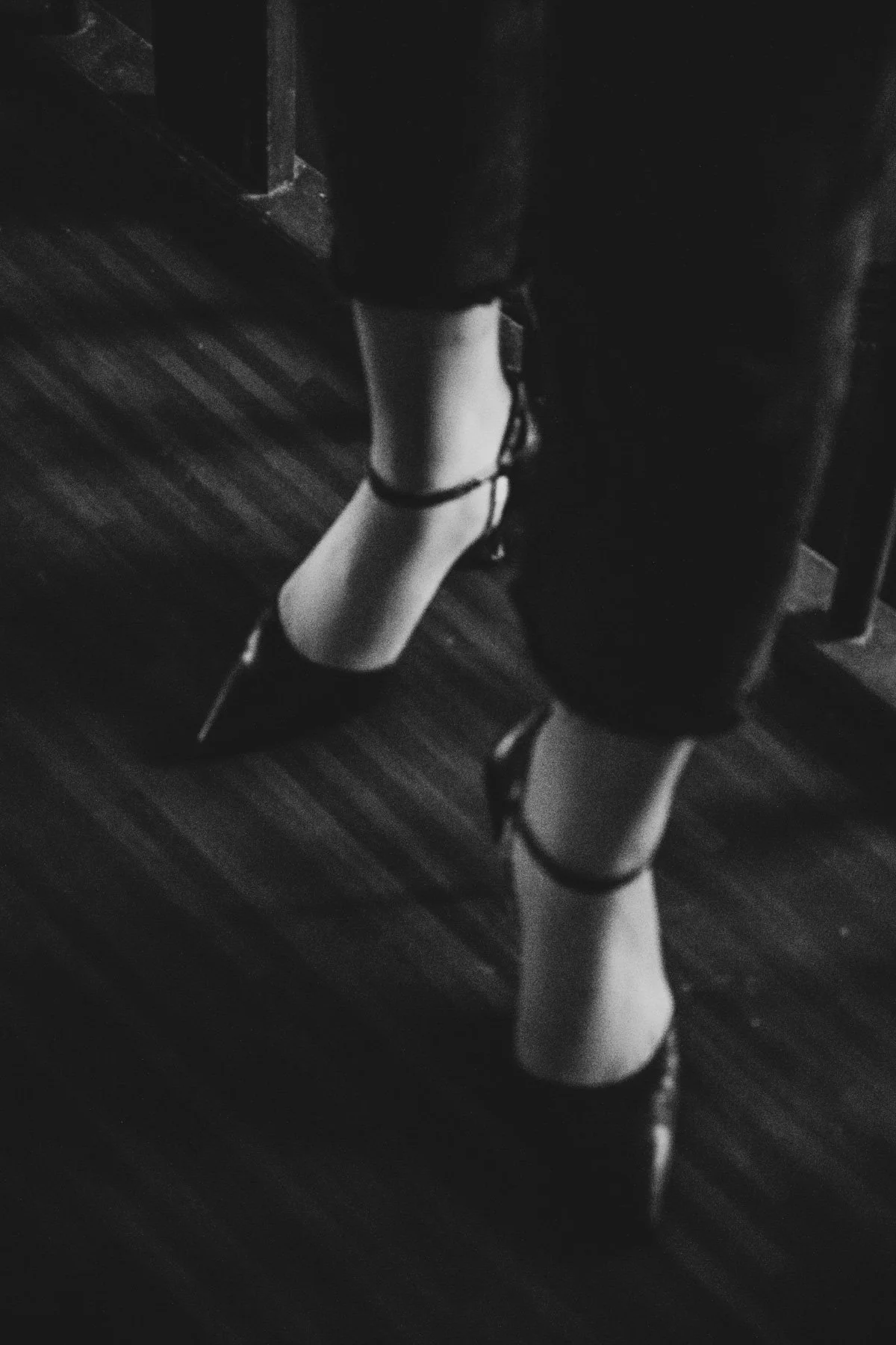 Legs in high heels on a dark stage floor, black-and-white detail from the Na'ama Goldman series — portrait by Janina Laszlo, portrait photographer in Munich