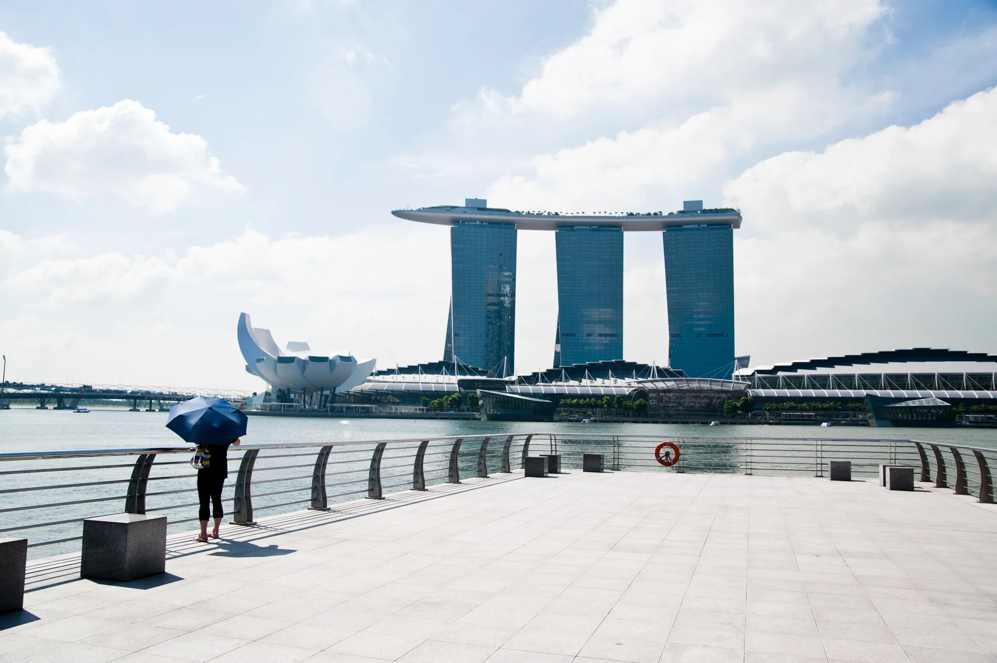 Woman with an umbrella on the promenade facing Marina Bay Sands and the ArtScience Museum — Singapore, architecture and travel photography by Janina Laszlo