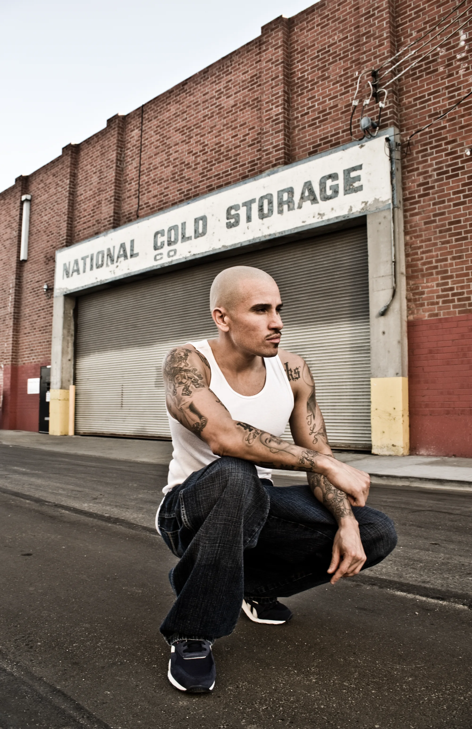 Artist crouching in front of a cold storage building in East Los Angeles — Suspect Entertainment, music portrait photography by Janina Laszlo