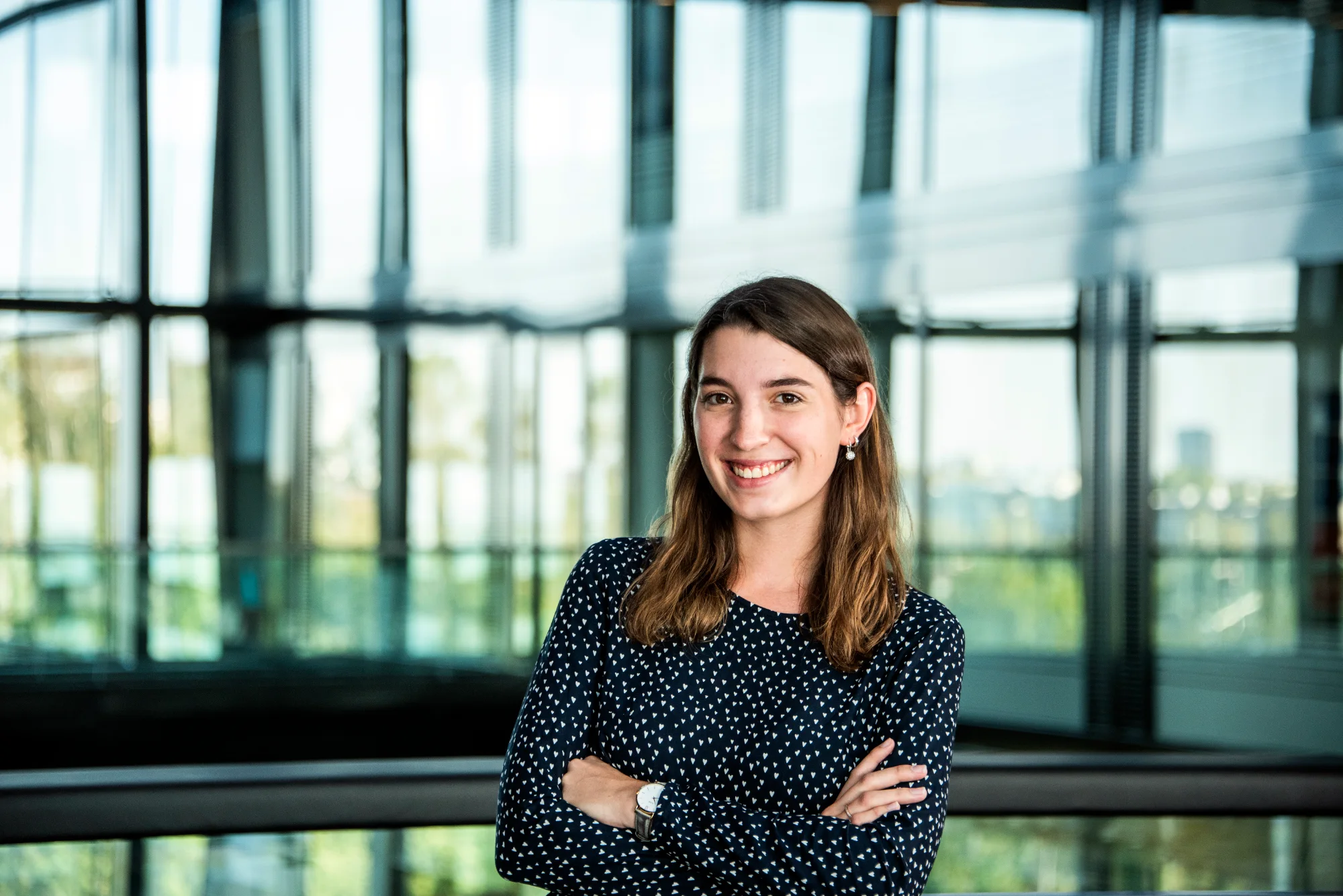 Smiling employee in a dark blouse in front of glass facades — SWMH, employer branding photography by Janina Laszlo