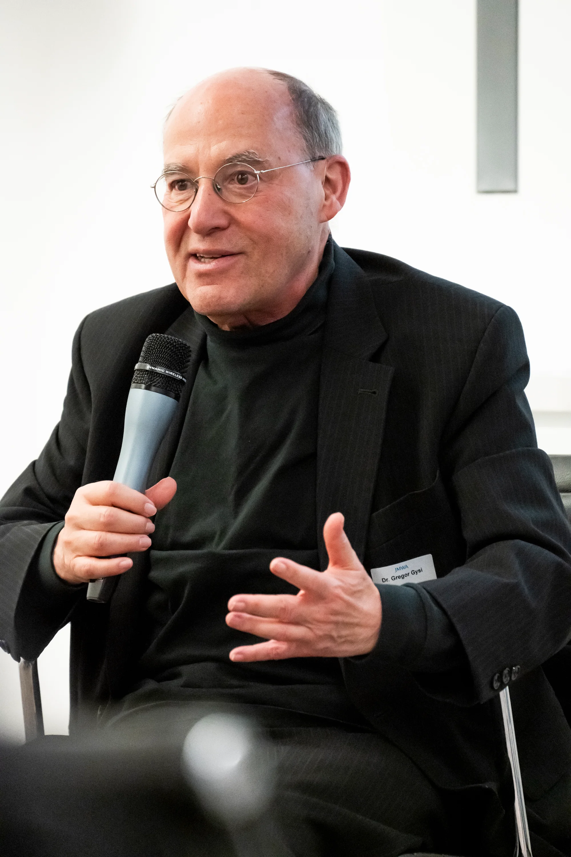 Gregor Gysi gesturing while talking, seated with microphone — Taylor Wessing with Gregor Gysi, corporate event photography by Janina Laszlo, Munich