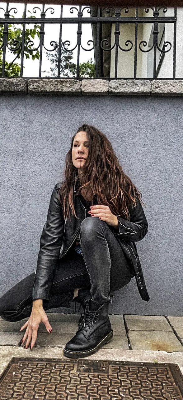 Jasmin Zelenko in a leather jacket crouching against a grey wall, Slovenia — Deutsche Telekom FaceTime Session, commercial and lifestyle photography by Janina Laszlo