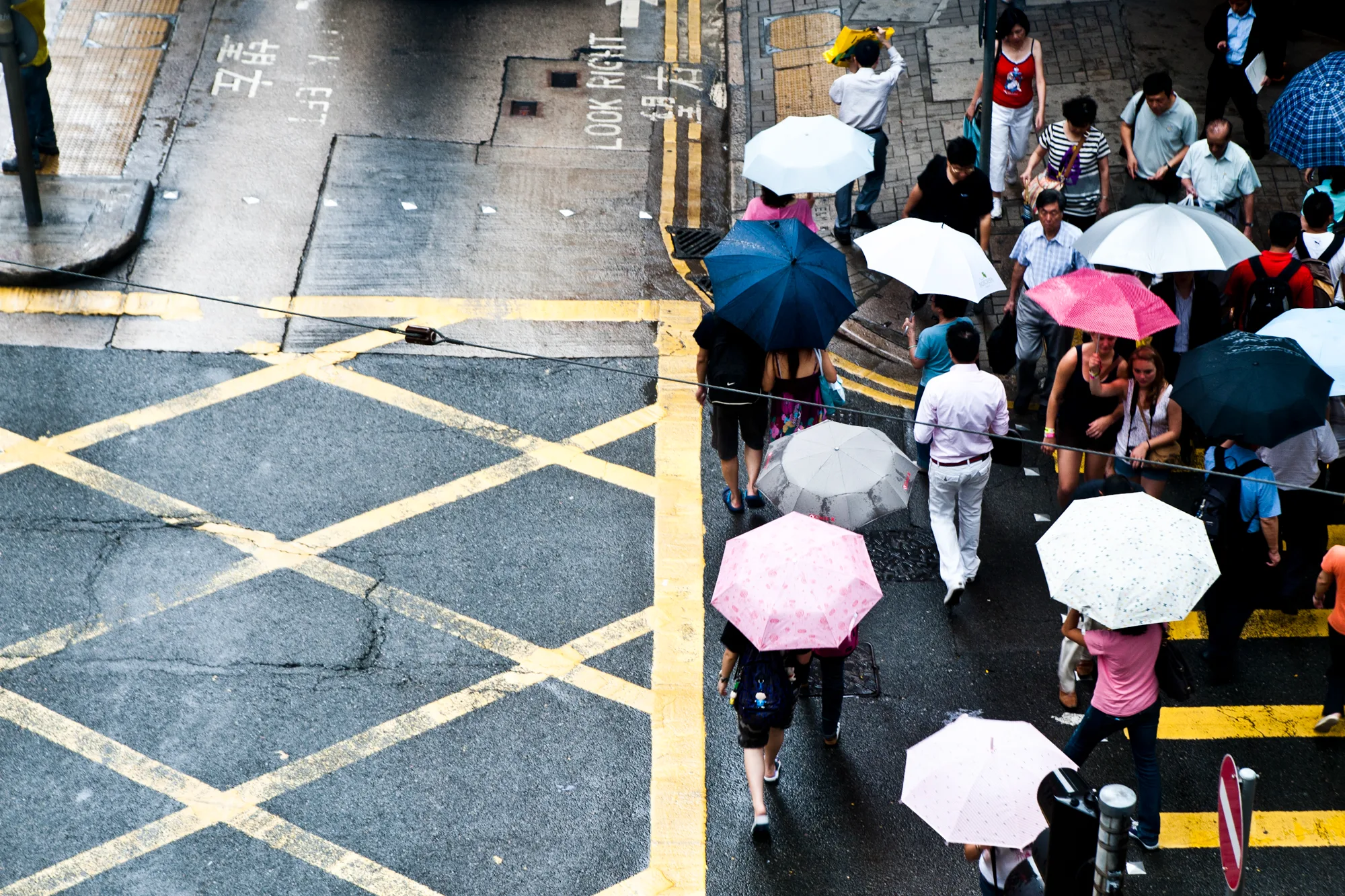 Pedestrians with colourful umbrellas crossing a rain-wet street, Hong Kong — Travel Notes, travel photography by Janina Laszlo