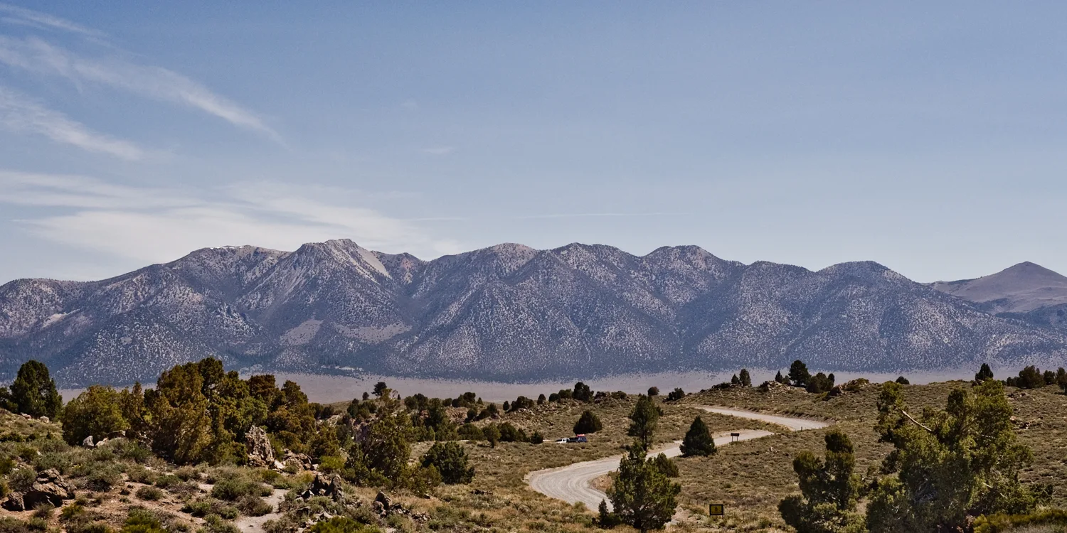Sierra Nevada range above a winding gravel road through sagebrush and pines, Eastern Sierra, California — US West Coast, panoramic fine art landscape photography by Janina Laszlo