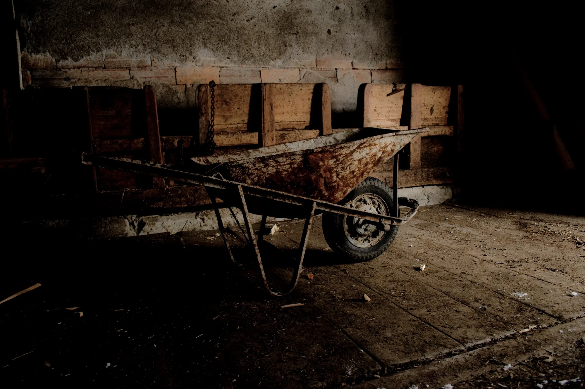 Rusty wheelbarrow in a dim old stable, Ziroger Alm — South Tyrol, fine art winter photography by Janina Laszlo