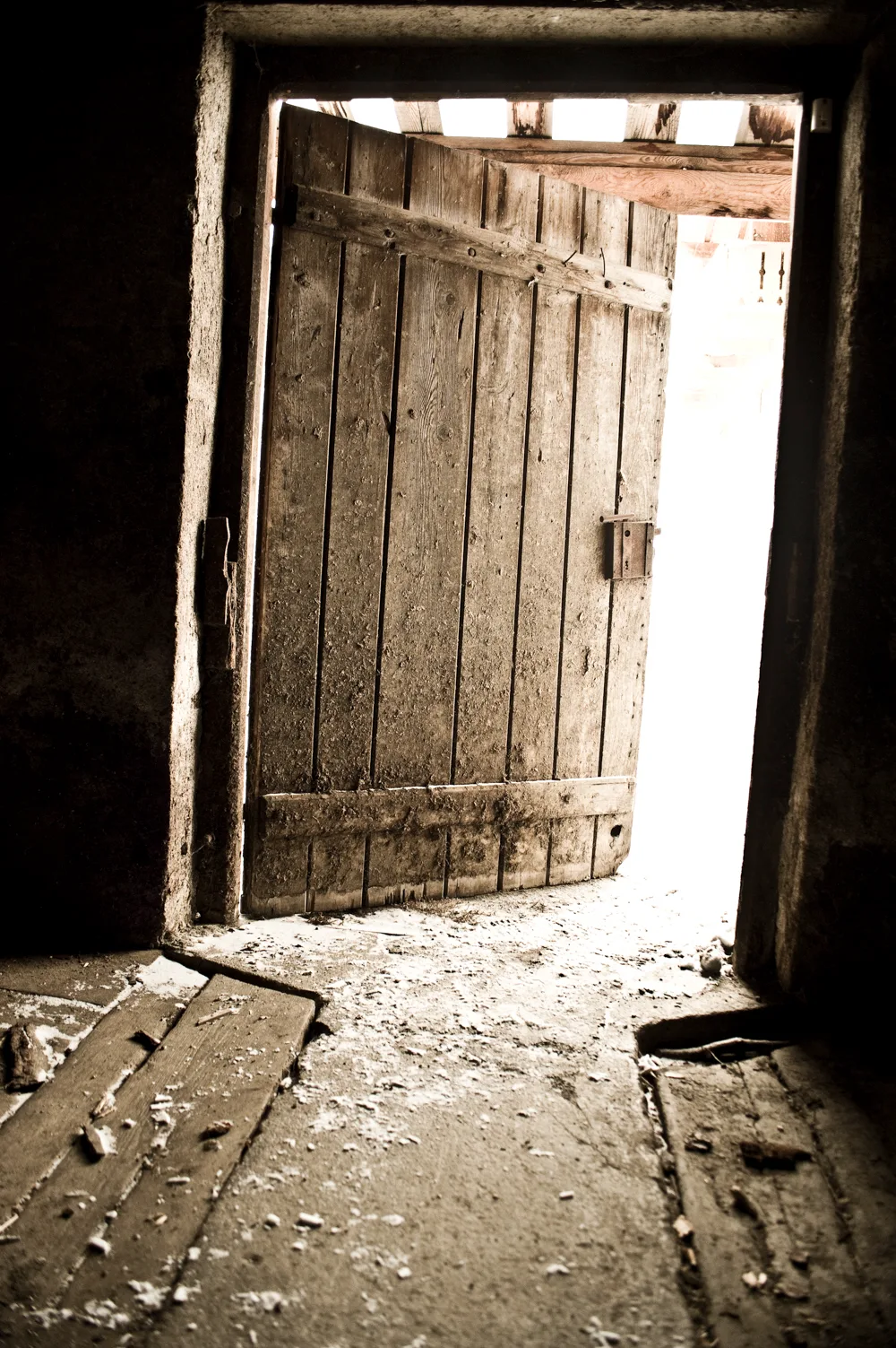 Weathered wooden barn door opening onto bright snow light, Ziroger Alm — South Tyrol, fine art winter photography by Janina Laszlo