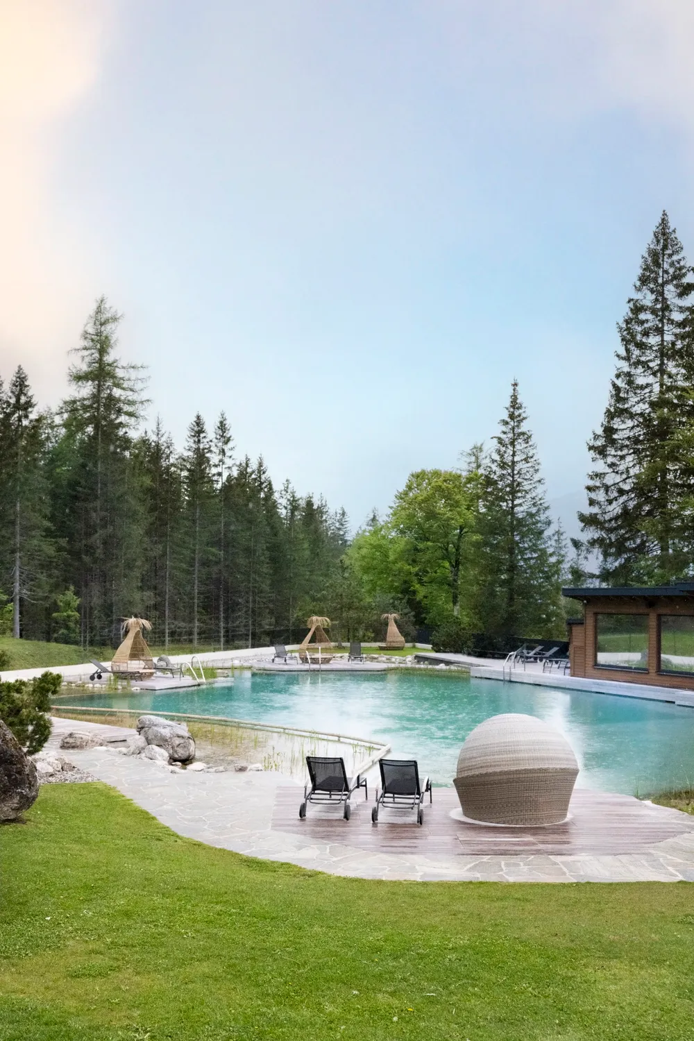 Natural swimming pond with sun loungers and pine trees, Zugspitz Resort, Ehrwald — campaign photography by Janina Laszlo, Munich